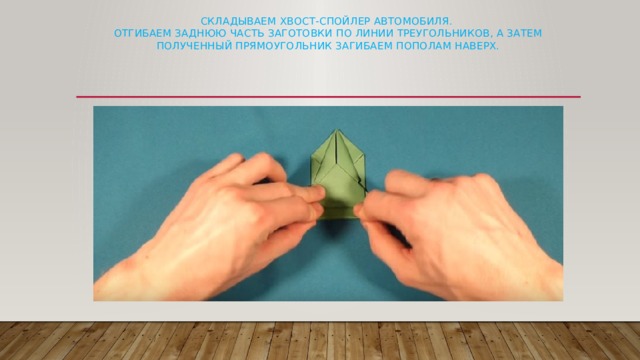 Складываем хвост-спойлер автомобиля.  Отгибаем заднюю часть заготовки по линии треугольников, а затем полученный прямоугольник загибаем пополам наверх.   